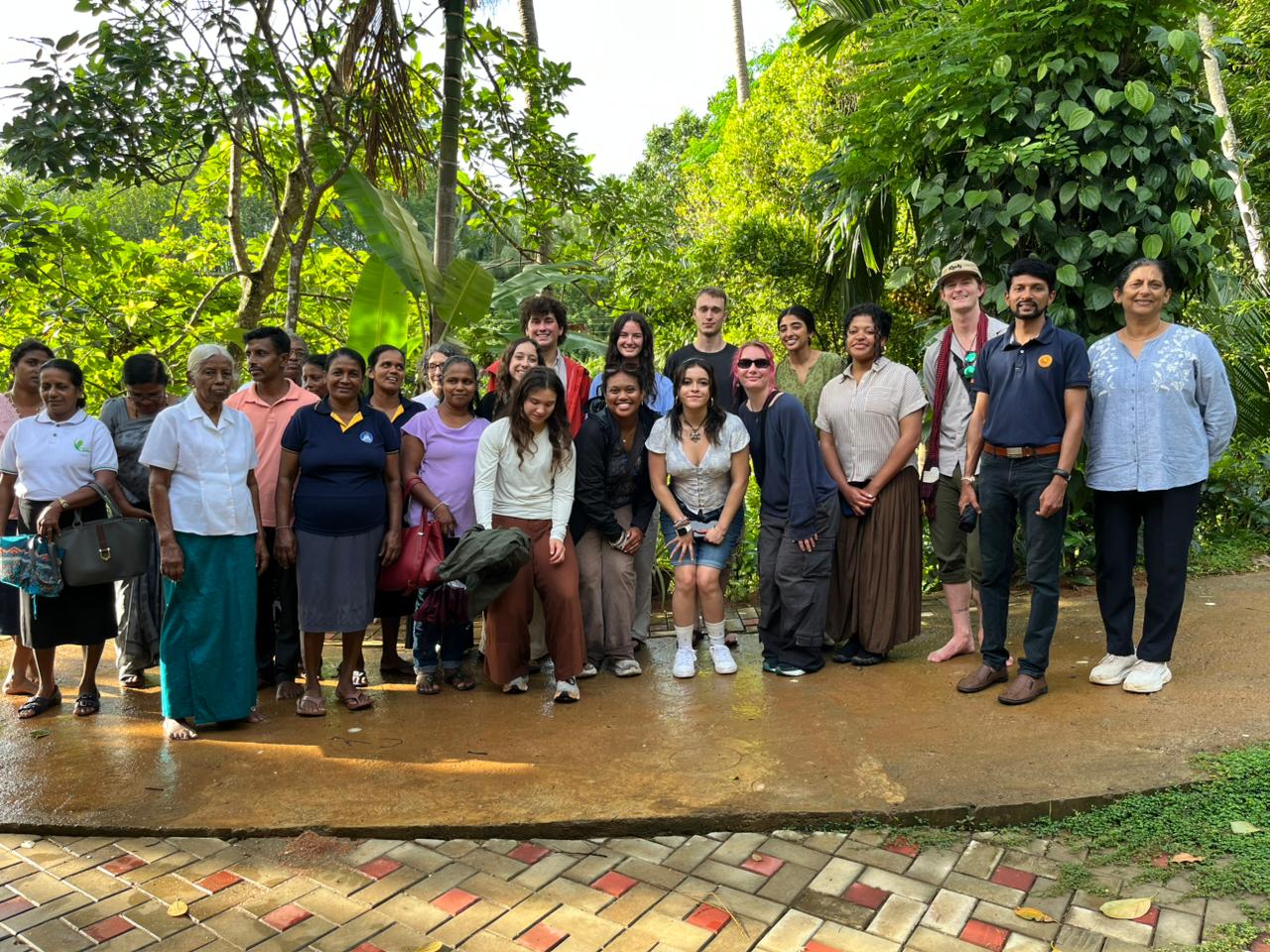 Visiting foreign university students standing with CDC members and community women outside the centre